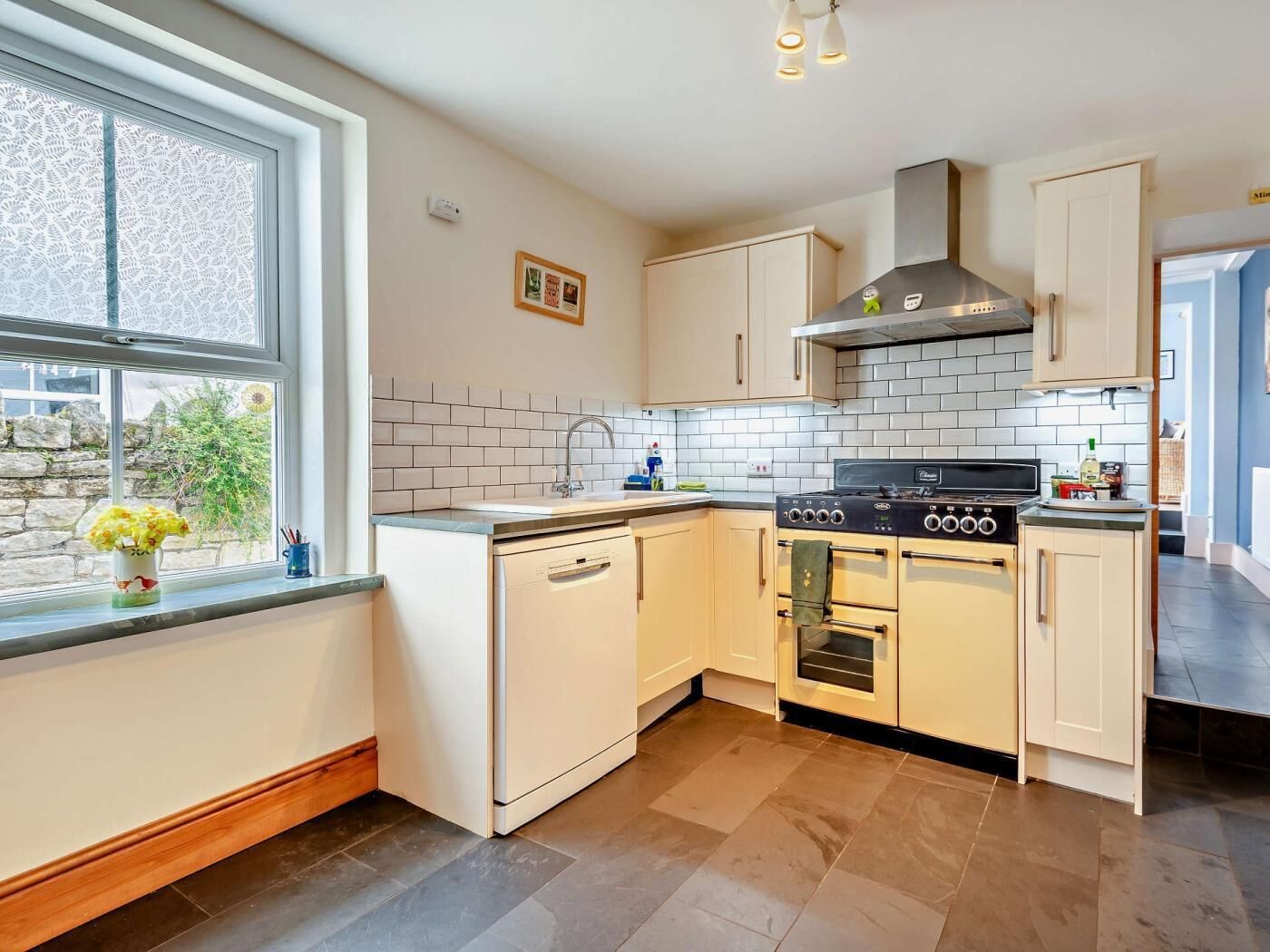 A modern kitchen with white cabinets, a black stove, and a window with a view of greenery.