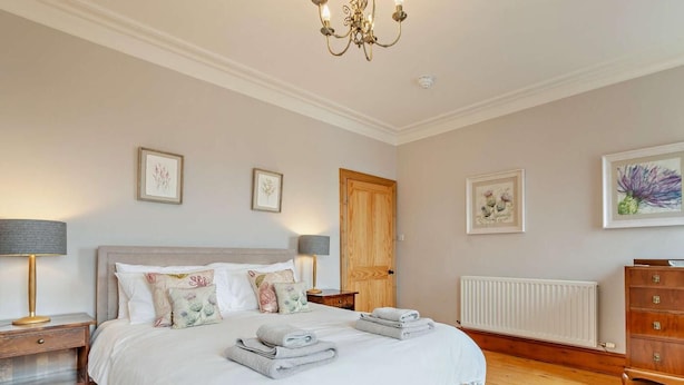 Een slaapkamer met een bed, nachtkastjes, een dressoir, een radiator en wanddecoratie.