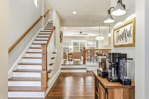 A staircase with wooden steps and handrails, a coffee maker on a counter, and a 'Thankful' sign on the wall. - The Clifton | Bars, Bourbon, and Brunch on Foot | Sleeps 15 (Louisville)