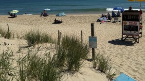 Een strand met zand, gras en een blauwe mat.