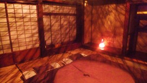 Une pièce traditionnelle avec un sol recouvert de tatamis, des portes coulissantes et une petite table basse.