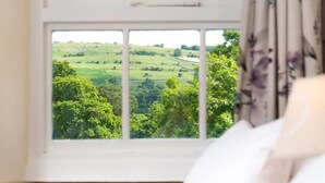 A room with a large window offering a view of a green landscape. - 2 Bed in Penrith (oc-sz271) (Bampton)