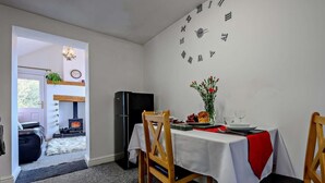 A dining area with a table set for two, a black refrigerator, and a wall clock. - 1 Bed in Penrith (oc-sz254) (Hutton)