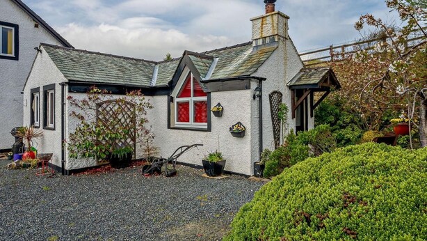 A quaint house with a gravel driveway, a red window, and a chimney. - 1 Bed in Penrith (oc-sz254) (Hutton)