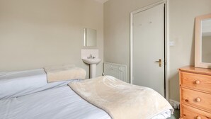 A bedroom with two beds, a bedside table, a dresser, a mirror, and a radiator. - 5 Bed in Keswick (oc-sz291) (Keswick)