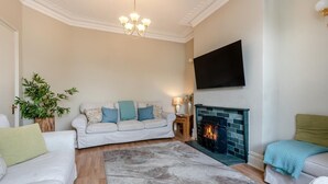 A living room with a sofa, a fireplace, a television, and a plant. - 5 Bed in Keswick (oc-sz291) (Keswick)
