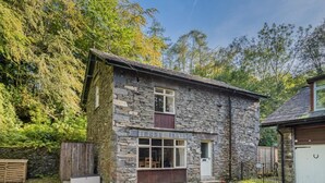 Ein Haus aus Stein mit einem großen Fenster, einer Tür und einer kleinen Veranda.