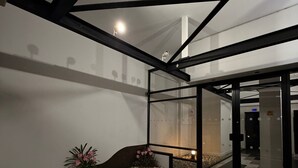 Un bâtiment moderne doté d’une façade en verre, d’un chemin en pierre et d’un petit jardin agrémenté de fleurs roses.