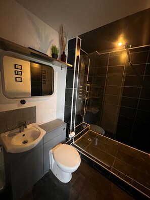 Et moderne badeværelse med toilet, vask og brusekabine med glasvægge.
