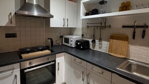 Une cuisine moderne avec des armoires blanches, une hotte en acier inoxydable, un four à micro-ondes, un grille-pain et une planche à découper en bois.