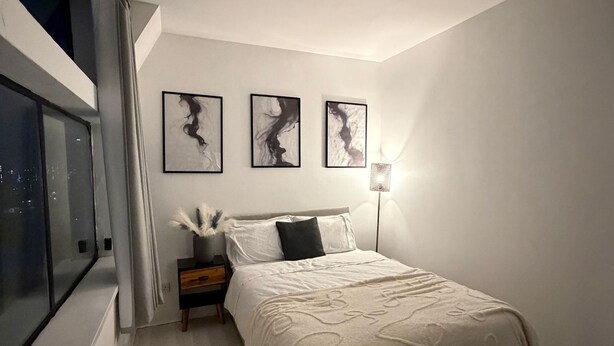 Une chambre à coucher comprenant un lit, une table de chevet, une lampe et trois œuvres d’art accrochées au mur.