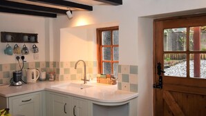 A kitchen with a sink, countertop, and cabinets. There is a window with a view of a garden. - 3 Bed in Holmrook (oc-sz313) (Boot)