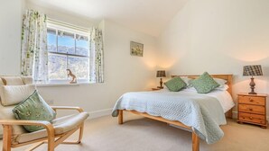 A bedroom with a bed, a chair, a nightstand, a lamp, and a window with curtains. - 3 Bed in Keswick (oc-sz234) (Borrowdale)