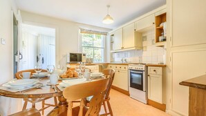A kitchen with a dining table set for four, a microwave, oven, and cabinets. - 3 Bed in Keswick (oc-sz234) (Borrowdale)