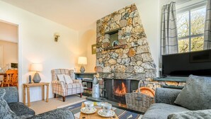 A cozy living room with a stone fireplace, comfortable seating, and a television. - 3 Bed in Keswick (oc-sz234) (Borrowdale)