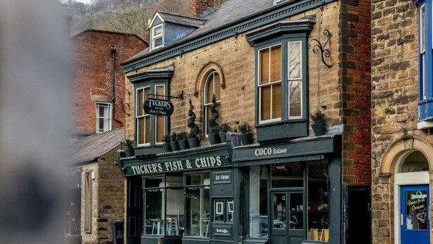 A traditional pub with a sign for 'Tuckers Fish & Chips' and a coffee shop named 'Coco Italiano' across the street. - 5 Bed in Matlock Bath (oc-85188) (Matlock Bath)