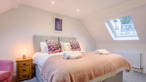 A bedroom with a bed, bedside table, lamp, and a window with a view. - 5 Bed in Matlock Bath (oc-85188) (Matlock Bath)