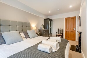 Ein Schlafzimmer mit einem großen Bett, einem Nachttisch, einer Kommode, einem Sessel und einer Tür.