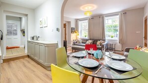 Eine moderne Küche mit Essbereich, einer Couch und Blick ins Freie.
