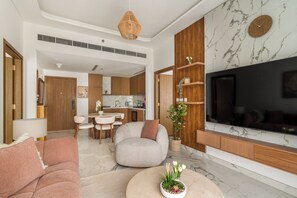 A modern living room with a sofa, a coffee table, and a TV mounted on a wall with a marble pattern. - Silkhaus Azizi Riviera67 (Dubai)