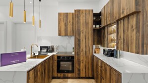 A modern kitchen with wooden cabinets, a built-in oven, and a marble countertop. - Silkhaus Azure Residences (Dubai)