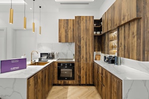 Eine moderne Küche mit Holzausstattung, integriertem Backofen und einer Marmorarbeitsplatte.
