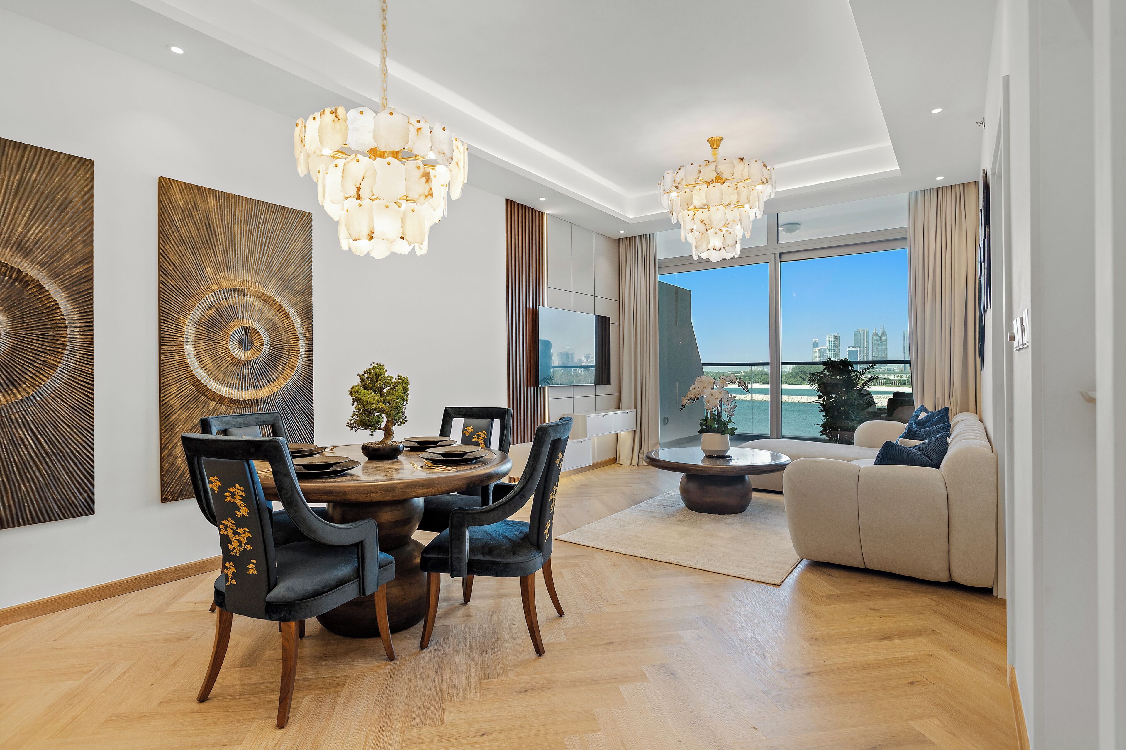 A modern living room with a dining area, large windows, and a view of the city skyline.