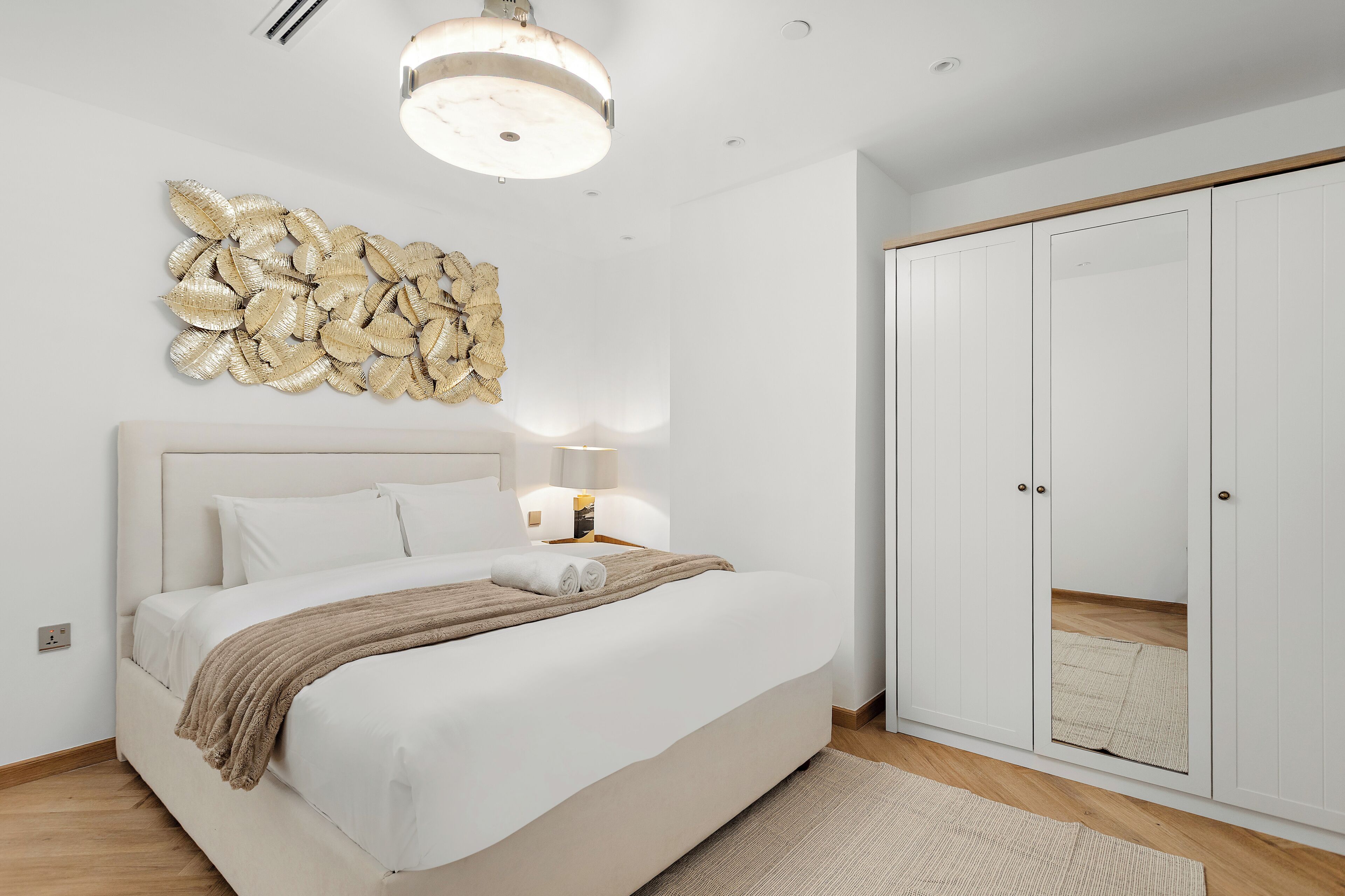 A hotel room with a bed, bedside lamp, and a wardrobe.