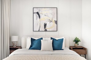 A bedroom with a bed, pillows, a bedside table, a lamp, and a wall-mounted abstract painting. - Silkhaus Centrium (Dubai)
