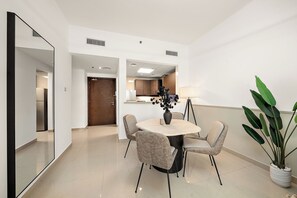 A modern dining area with a round table, four chairs, a vase with flowers, and a large potted plant. - Silkhaus Centrium (Dubai)