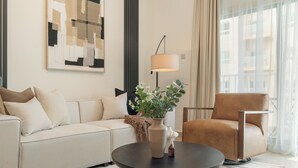Una sala moderna con un sofá, un sillón, una mesa de centro y un cuadro en la pared.