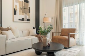 A modern living room with a sofa, armchair, coffee table, and a painting on the wall. - Silkhaus Centrium (Dubai)