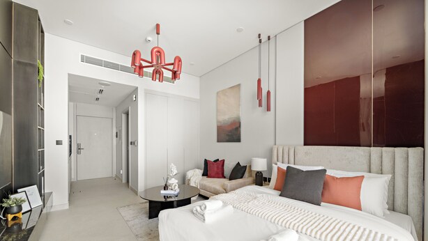 A modern hotel room with a large bed, a sitting area with a sofa, a coffee table, and a painting on the wall. - Silkhaus Hyde Walk (Dubai)