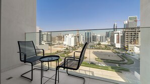 A balcony with two chairs and a small table, overlooking a cityscape with modern buildings and construction cranes. - Silkhaus Hyde Walk (Dubai)