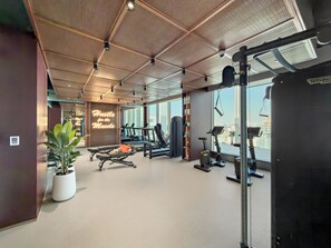 A gym with exercise equipment, a motivational wall, and large windows. - Silkhaus Hyde Walk (Dubai)