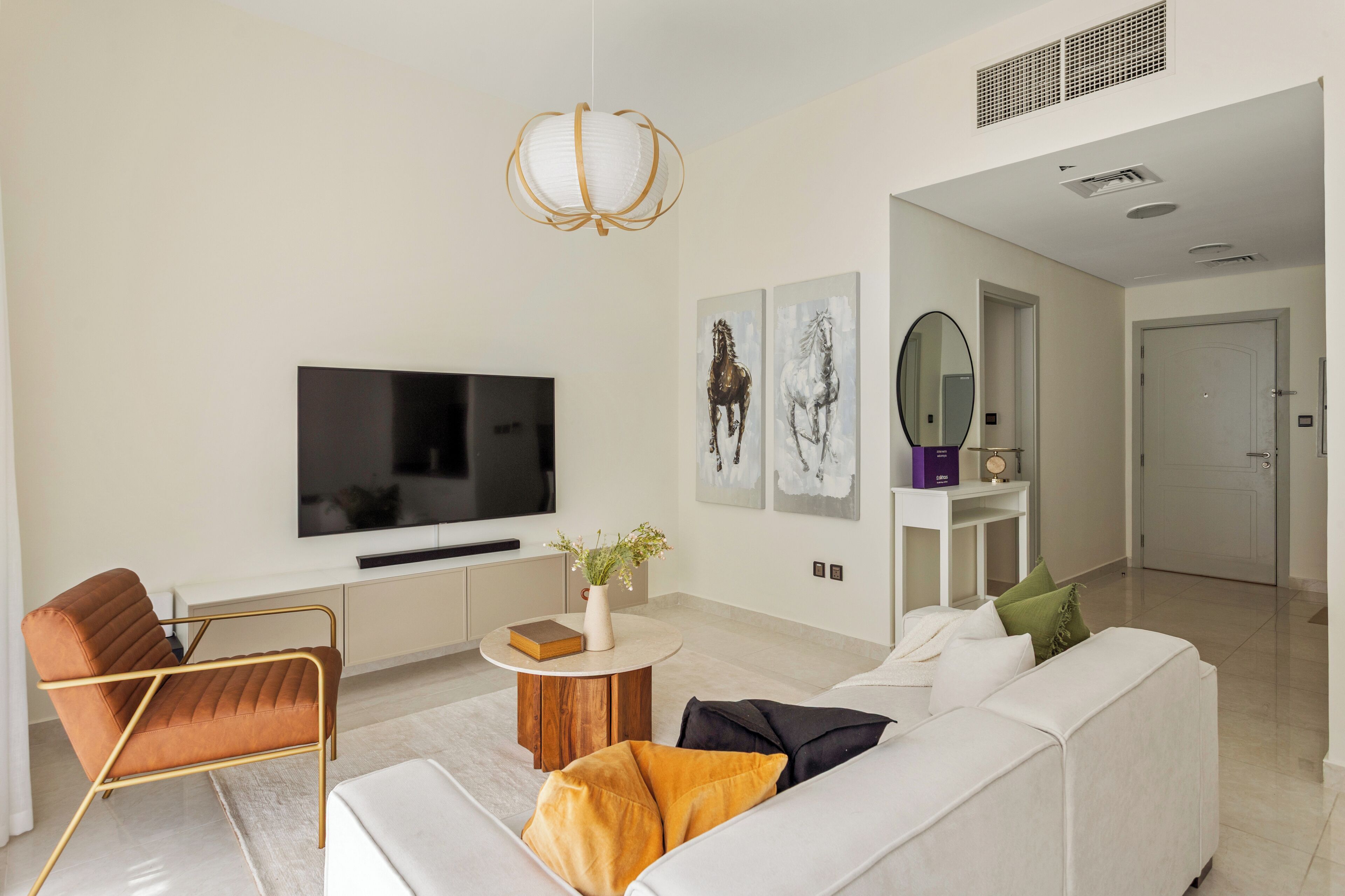 Ein modernes Wohnzimmer mit Flachbildfernseher, einer Couch, einem Couchtisch und einer dekorativen Vase.