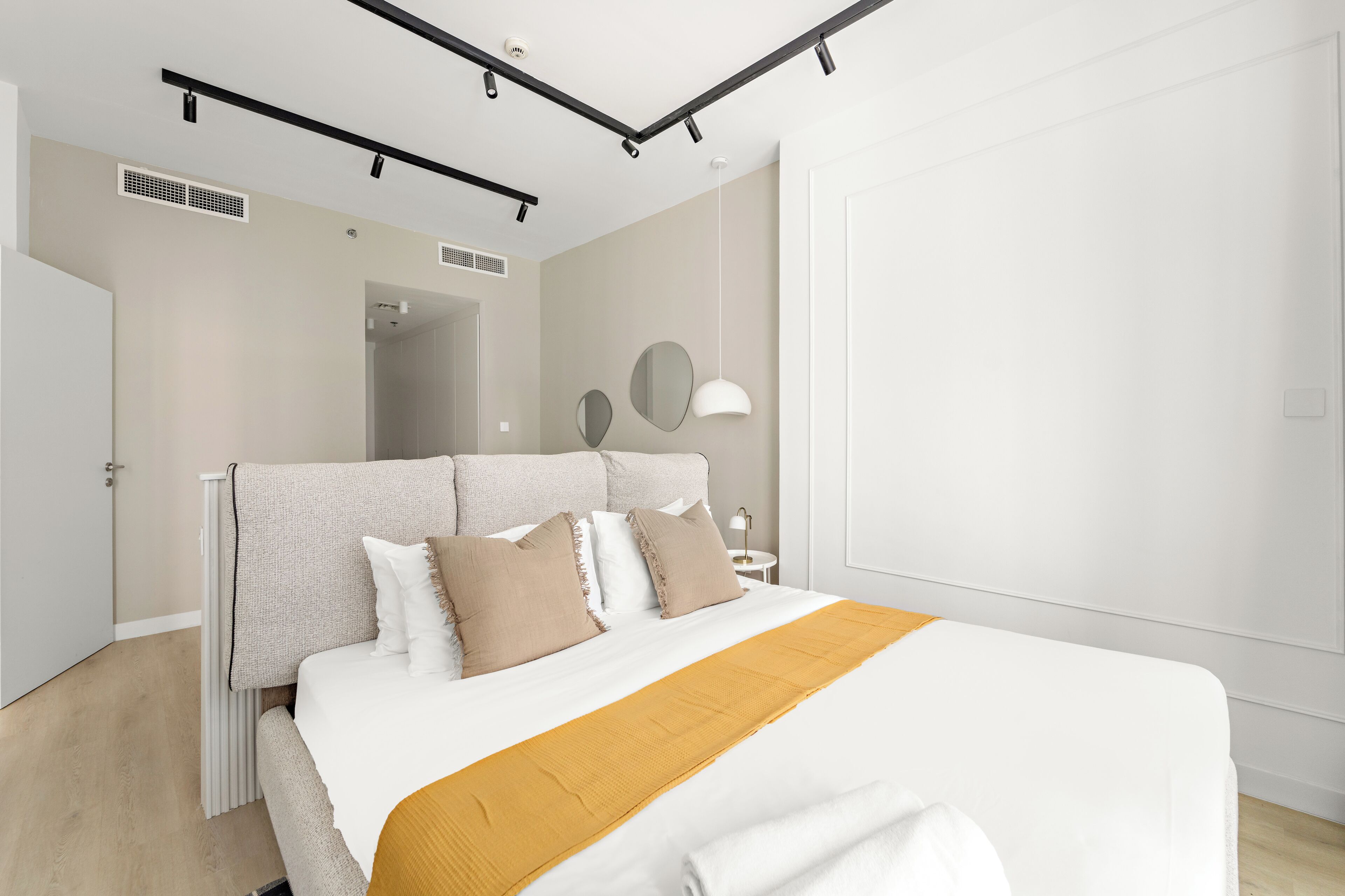 Un dormitorio moderno con cama, mesitas de noche, un espejo y una puerta.