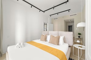 A modern hotel room with a large bed, a bedside table, a lamp, and a view of the hallway. - Silkhaus Torche Tower (Dubai)