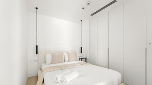 Quarto moderno com uma cama grande, uma mesa de cabeceira e um guarda-roupa.