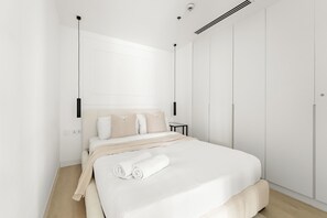Ein modernes Schlafzimmer mit einem großen Bett, einem Nachttisch und einem Kleiderschrank.