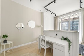 A minimalist child's room with a white desk, two wall mirrors, a potted plant, and a window with curtains. - Silkhaus Torche Tower (Dubai)