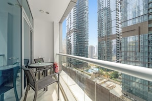A balcony with a glass table and chairs, a fire extinguisher, and a view of high-rise buildings. - Silkhaus Torche Tower (Dubai)