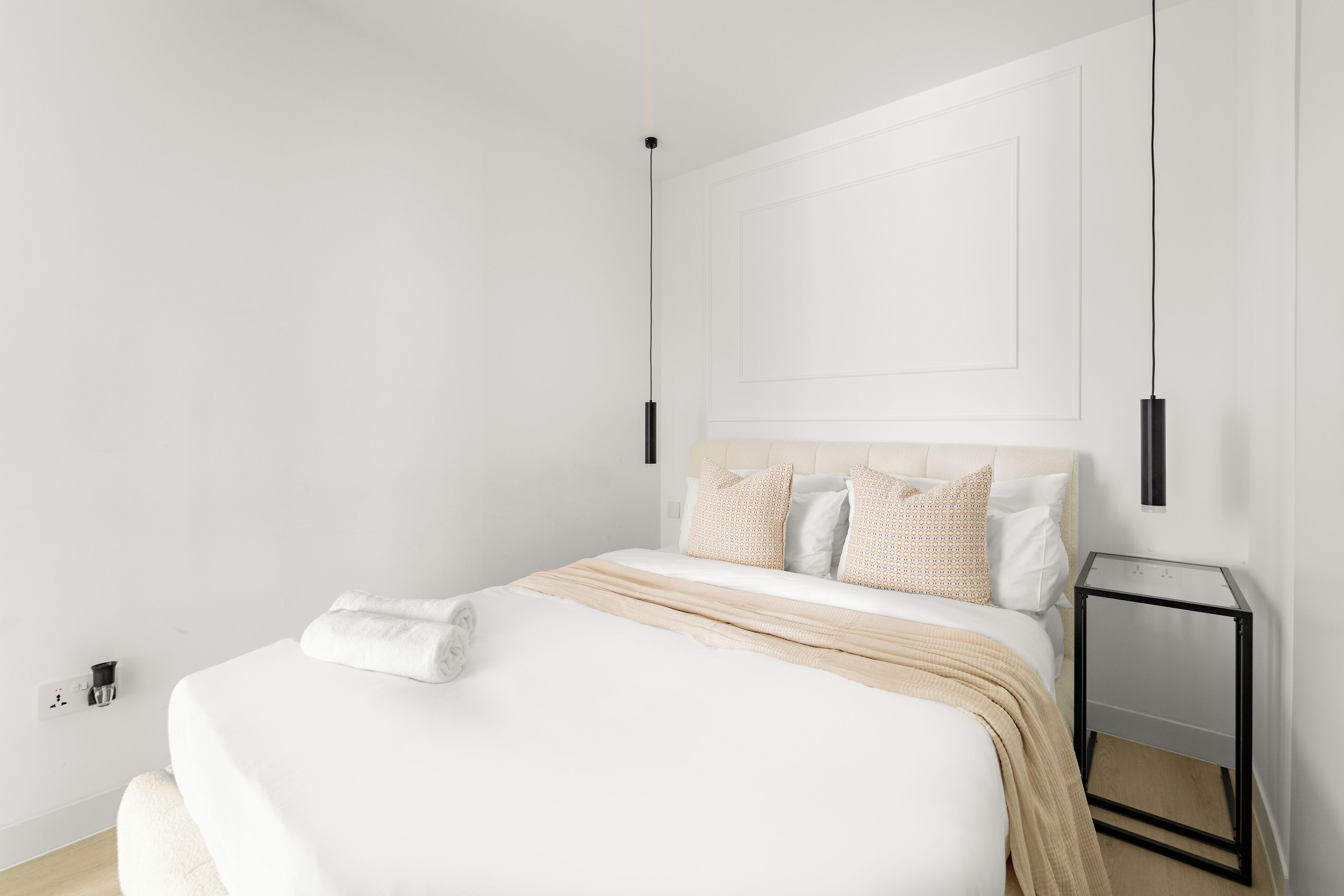A minimalist bedroom with a bed, bedside table, and wall-mounted light fixture.