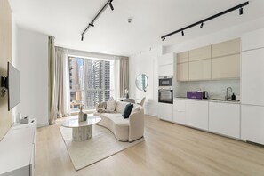 A modern living room with a sofa, a coffee table, and a view of tall buildings through large windows. - Silkhaus Torche Tower (Dubai)