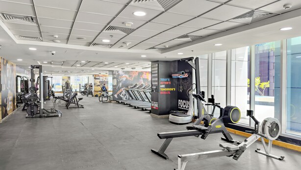 Uma academia com diversos equipamentos de exercícios, um espelho grande e cartazes motivacionais nas paredes.