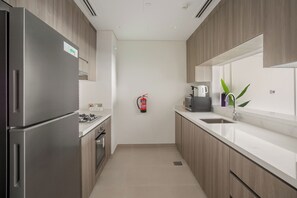 Una cocina moderna con electrodomésticos de acero inoxidable, gabinetes de madera, una cafetera y un extintor.