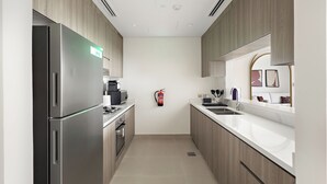 Una cocina moderna con electrodomésticos de acero inoxidable, armarios de madera y encimera blanca.