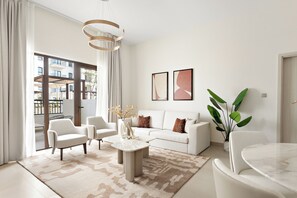 Una sala de estar moderna con un sofá, sillas, una mesita de centro y un ventanal grande.