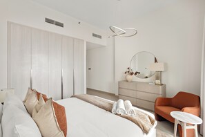 A modern hotel room with a large bed, a chest of drawers, a round mirror, and a small table. - Silkhaus Yas Golf Collection (Abu Dhabi)