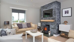 Una sala de estar moderna con chimenea, un sofá, una mesa de centro y un televisor montado en la pared.